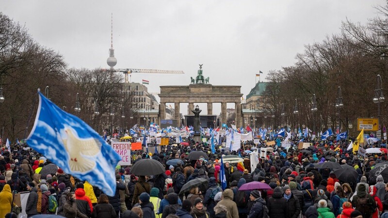 Teilnehmer einer Demonstration für Verhandlungen mit Russland stehen vor dem Brandenburger Tor. Am Brandenburger Tor in Berlin haben sich mehrere Tausend Menschen zu einer Kundgebung für Verhandlungen mit Russland im Ukraine-Krieg versammelt.