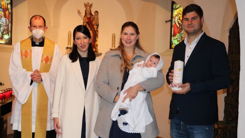 Taufpatin Stefanie Hofstetter, die den Täufling in den Armen hält, die Eltern undK aplan Matthias Meckel nach der Taufe.
