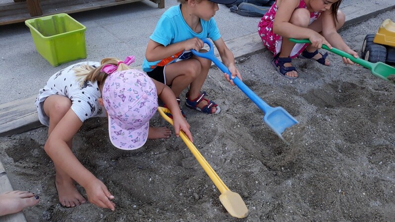 Die Kinder bei der Edelsteinsuche im Sandkasten.