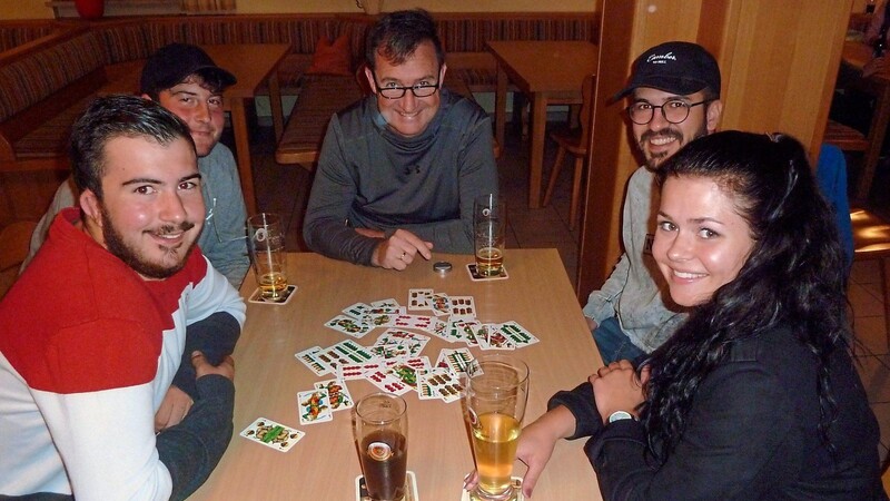 Eine Gruppe beim Schafkopfkurs, voller Freude beim Erlernen des alten bayerischen Kartenspiels.