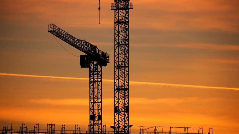 Baukräne stehen im Sonnenaufgang. Nach Einschätzung führender Wirtschaftsinstitute verschlechtern sich die wirtschaftlichen Aussichten in Deutschland weiter