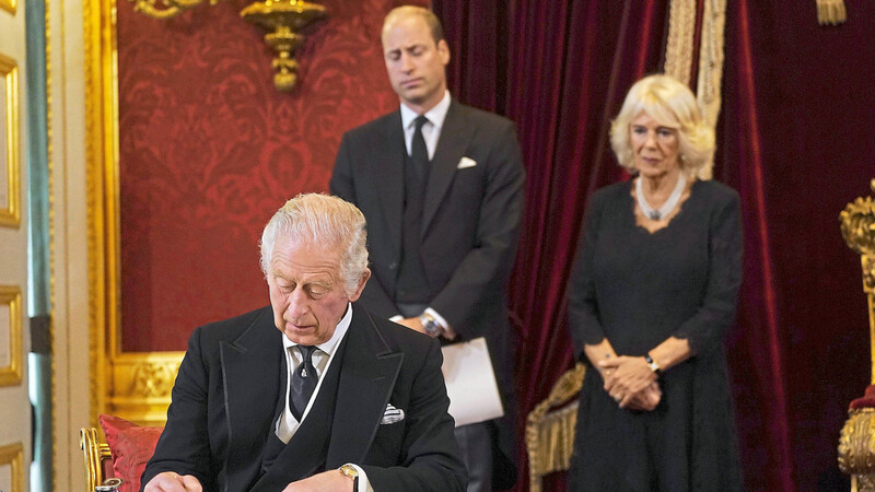 König Charles III. unterschreibt im Beisein seines Sohnes, Prinz William, und seiner Gemahlin, Königin Camilla, einen Eid.