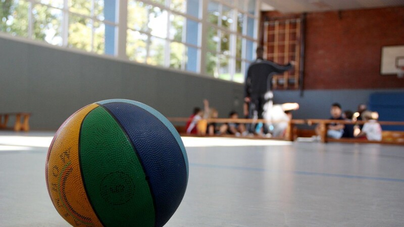 Ein Basketball liegt auf dem Boden einer Sporthalle.