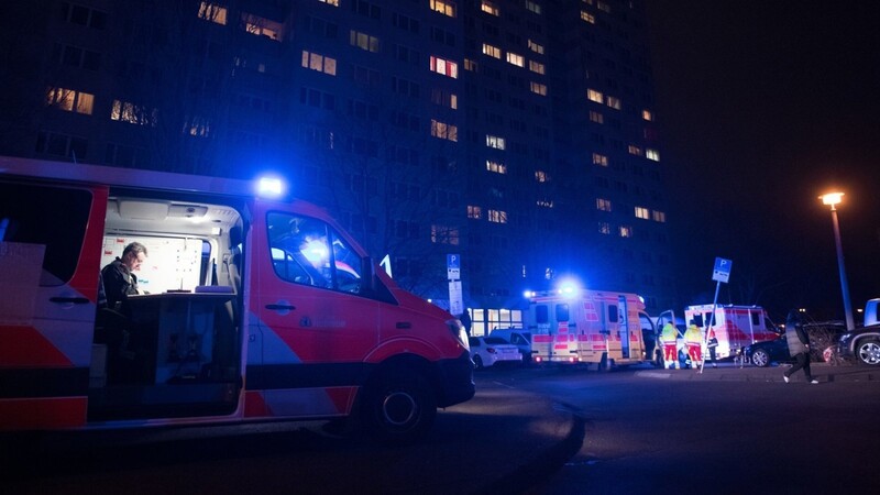 Ein Einsatzfahrzeug der Feuerwehr und ein Rettungswagen stehen mit eingeschaltetem Blaulicht an einem Hochhaus an der Landsberger Allee. Dort brannte es in der zehnten Etage des 18 Stockwerke hohen Gebäudes.