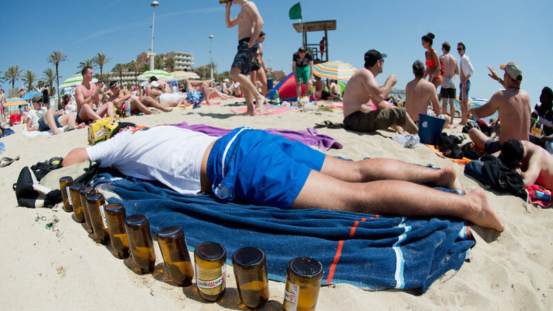Ein Tourist liegt am 06.06.2013 schlafend auf einer Luftmatratze neben leeren Bierflaschen am Strand von Arenal auf der Mittelmeerinsel Mallorca (Spanien).