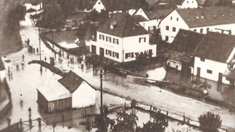 Ernst Gruß zeigt in seinem Heimatbuch eine Aufnahme von 1954. Zu sehen ist die von einem Hochwasser überschwemmte Bahnhofsstraße.