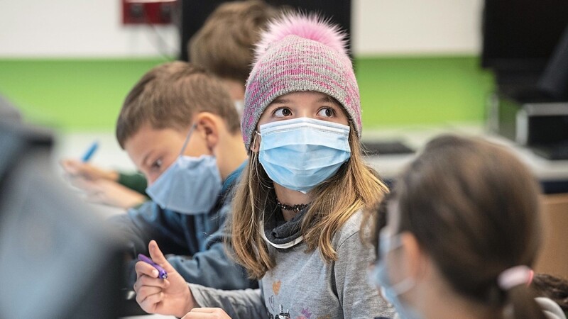Mit Mundschutzmasken sitzen Schülerinnen und Schüler im Unterricht