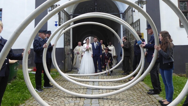 Das Brautpaar nach dem Verlassen der Schlosskirche mit Monsignore Sperl, Vikar Matthias und Diakon Peintinger vor der Schlauchspirale der Feuerwehr Gehstorf, mit im Bild der Hochzeitslader.