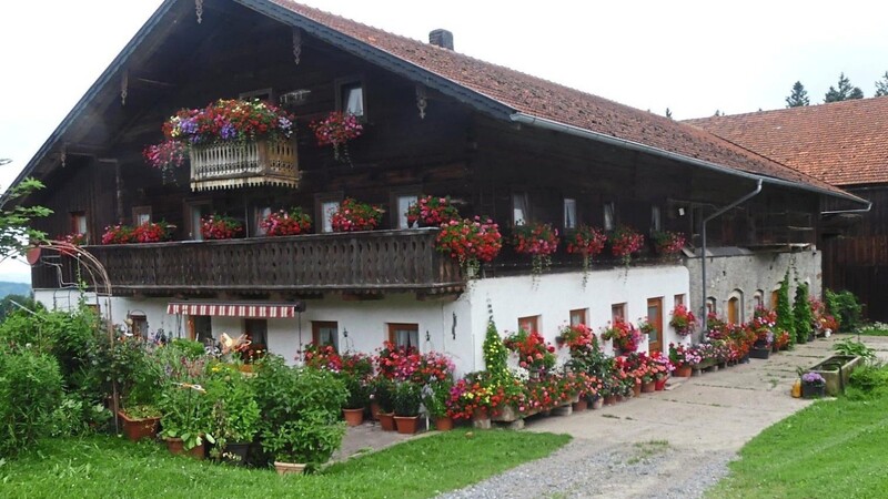 Das Bauernhaus der Familie Rinkl, unten gemauert und oben gezimmert, mit einem steinerner Wassergrand auf der "Gred" und am Giebel mit einem Kreuz versehen, im prächtigen Blumenkleid