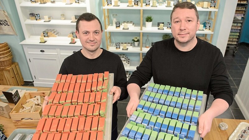 Cosmin Katko (v. l.) und Marc-Simon Wolf vom Seifenhersteller Haused Wolf halten in ihrem Laden in Nürnberg Tabletts mit den Seifen von der Sorte Macintosh (l) und Kentish Green in den Händen.