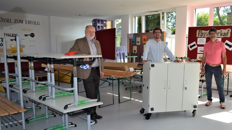 Bürgermeister Thomas Einwang mit der Schulleitung Dr. Simon Dörr und Markus Mayerhöfer (von links) vor Teilen der angelieferten neuen Möbel in der Aula.