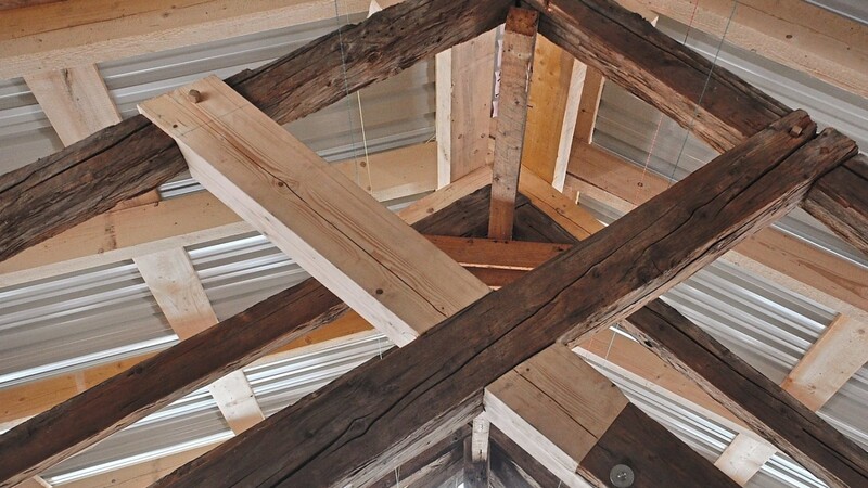Die alten und die neuen Balken bilden nebeneinander den sanierten Dachstuhl. Oben drüber schützt ein Behelfsdach den Bereich.