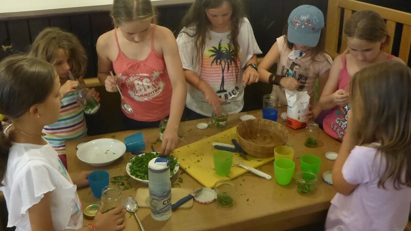 Mädchen bei einer Sommerfreizeit unter sich beim Zubereiten von Hustensaft aus Spitzwegerich.
