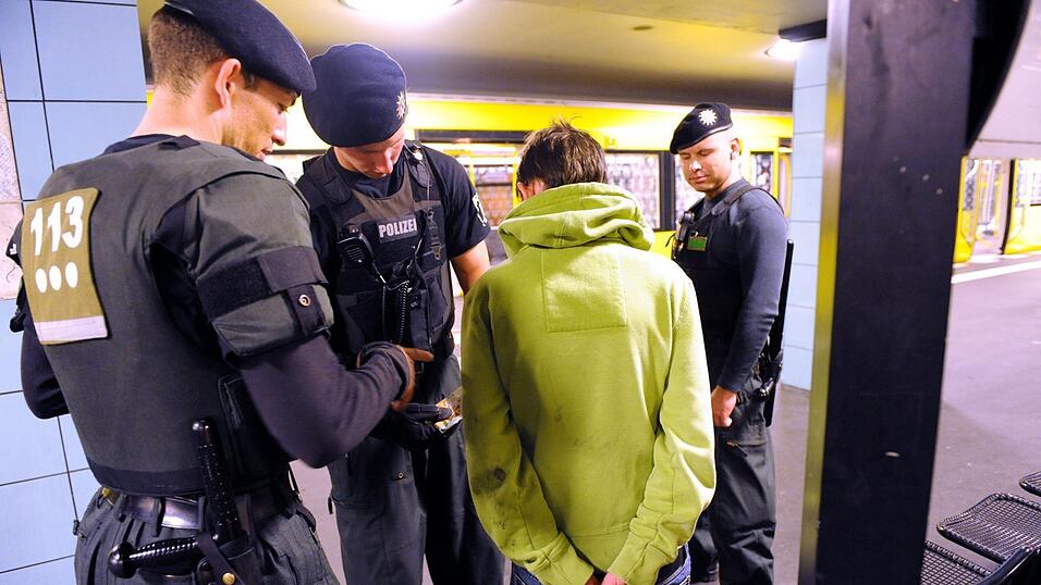 Polizeibeamte durchsuchen in einer U-Bahnstation in Berlin eine verd&auml;chtige Person.