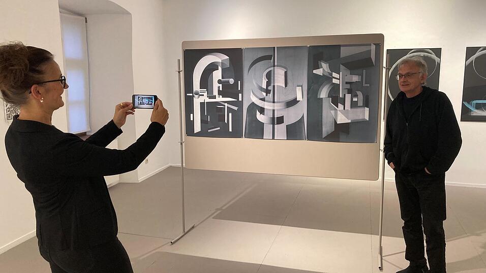 Galerieleiterin Anjalie Chaubal und Kurator Raoul Kaufer bei einem Werk von Barbara Herold. Sie l&auml;sst ihr Kunstwerk, das noch ganz ohne KI entstanden ist, mittels Handy-App und augmented Reality dreidimensional auf dem Display erscheinen.