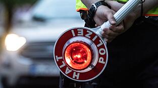 Ein Polizist hält bei einer Verkehrskontrolle eine Winkerkelle in der Hand. Ein Polizist hält bei einer Verkehrskontrolle eine Winkerkelle in der Hand.