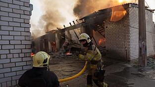 Rettungskr&auml;fte l&ouml;schen ein Feuer in einer Kiewer Autowerkstatt, die durch einen russischen Angriff besch&auml;digt wurde.