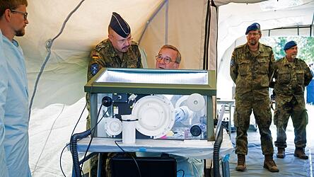 Bundesverteidigungsminister Boris Pistorius (M., SPD) sitzt bei einem Besuch der Sanitätsakademie der Bundeswehr an einer Glovebox. Gezeigt wird das mobile Labor des Instituts für Mikrobiologie der Bundeswehr.