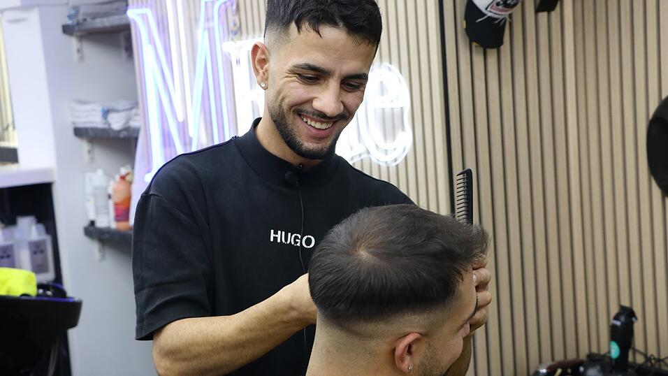 Hassan Jeejo könnte seine Haarschnitte vermutlich alle im Schlaf ausführen - sein Kunde Alessio bekommt seine Seiten frisch gekürzt und den Bart rasiert. Bei den Friseurbesuchen machen sie gerne 'Gaudi' zusammen. Hassan Jeejo könnte seine Haarschnitte vermutlich alle im Schlaf ausführen - sein Kunde Alessio bekommt seine Seiten frisch gekürzt und den Bart rasiert. Bei den Friseurbesuchen machen sie gerne 'Gaudi' zusammen.