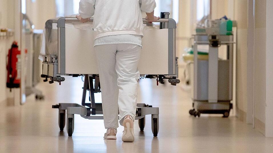 Eine Krankenpflegerin schiebt ein Krankenbett durch einen Flur.