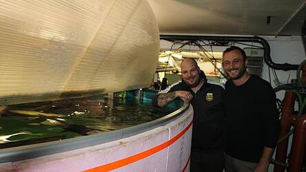Dominik Schmaderer (links) und Benedikt Burger vor einem Zuchtbecken, das im Keller eines ehemaligen Supermarktes untergebracht ist.
