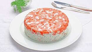 Willkommen auf unserer kulinarischen Reise! Das ist eine frische Lachs-Terrine. Die wesentlichen Zutaten sind Räucherlachs, Gurke, Sauerrahm, Zwiebeln und viel Dill. Schnell geht es auch, denn die Zubereitungszeit ist nur eine halbe Stunde. Aber dann muss die Lachstorte über Nacht im Kühlschrank fest werden.