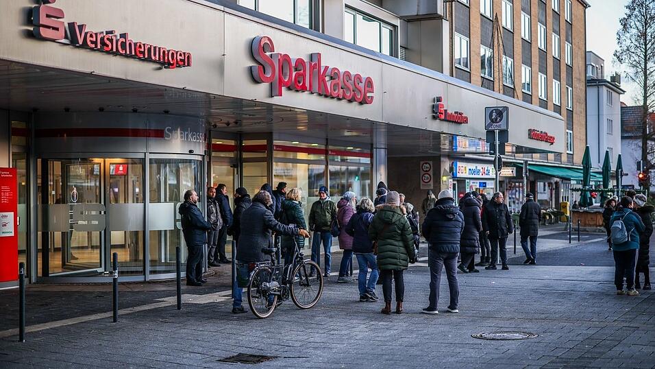Nach einem Einbruch in den Tresorraum einer Bankfiliale in Gelsenkirchen warten Menschen vor dem Eingang auf Informationen.
