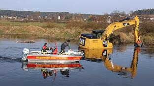 Nach einem technischen Defekt an der Hydraulikleitung steckt der Bagger im Regen fest. Einsatzkräfte der Feuerwehr Roding sichten das Umfeld vom Rettungsboot aus.