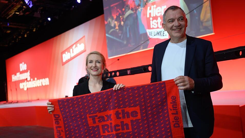 Die Linke-Parteivorsitzenden Ines Schwerdtner und Jan van Aken halten vor Beginn des Bundesparteitages ein Handtuch mit dem Spruch 'Tax the Rich' in ihren H&auml;nden.