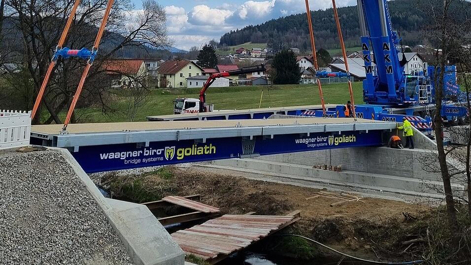 Millimeterarbeit: Die erste von drei Br&uuml;ckenelementen wurde am Dienstagmittag eingehoben. Die provisorische Br&uuml;cke &uuml;ber den Klinglbach wird 7,5 Meter breit und 24 Meter lang. Ab Mitte Mai soll der Verkehr &uuml;ber die Umfahrung rollen. Dann beginnt der Ersatzneubau der Klinglbachbr&uuml;cke bei Oberndorf.