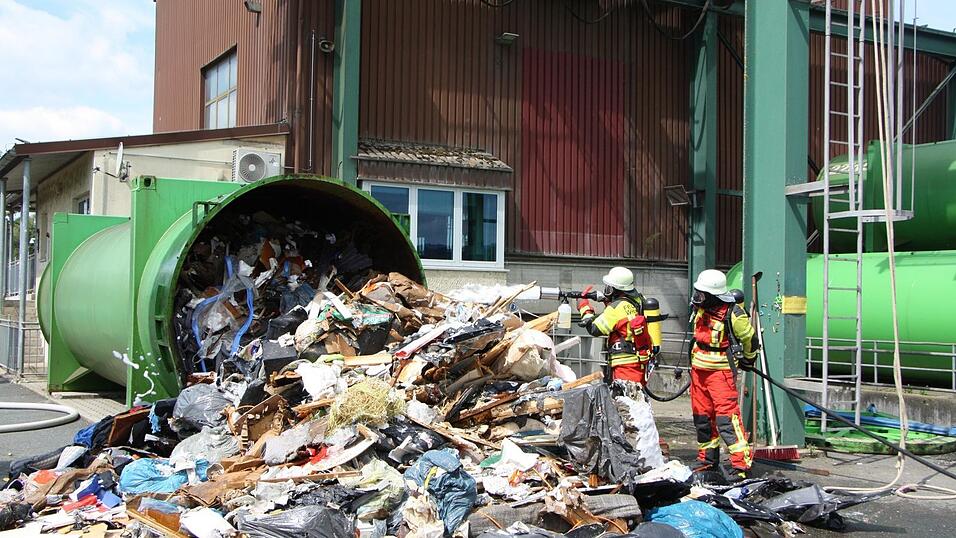 Die Feuerwehrleute löschen den Müllberg vorsichtshalber ab. Die Feuerwehrleute löschen den Müllberg vorsichtshalber ab.