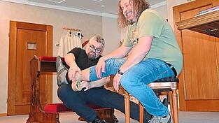 Der Pfarrer befestigt beim aufgezwungenen Gefangenen die Fu&szlig;fessel.