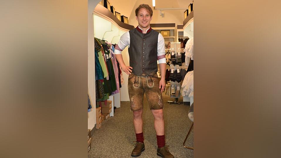 Das weiße Hemd hat rote Details. Dazu passt eine anthrazit-rote Weste. Die bordeauxroten Socken stimmen das Outfit farblich bis ins kleinste Detail ab.