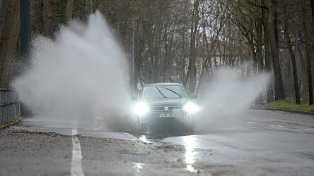 Ein Auto fährt durch eine Pfütze, so dass das Wasser zur Seite spritzt. Ist das Wasser auch noch schneematschdreckig, freuen sich Passanten über so etwas ganz besonders.