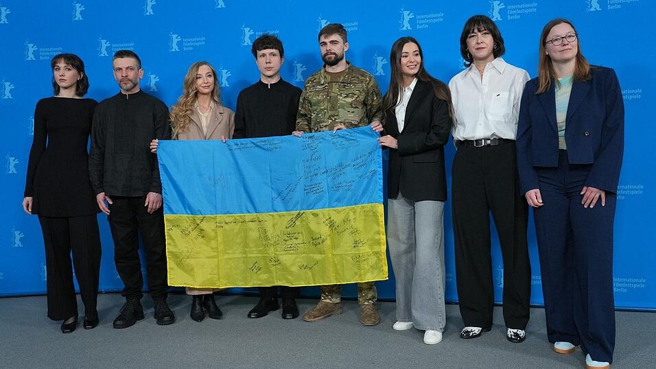 Das Team des Films «Strichka chasu» mit einer ukrainischen Flagge, auf der die Lehrerkollegen des Protagonisten und jetzigen Soldaten Borys Khovriak (M) unterschrieben haben.