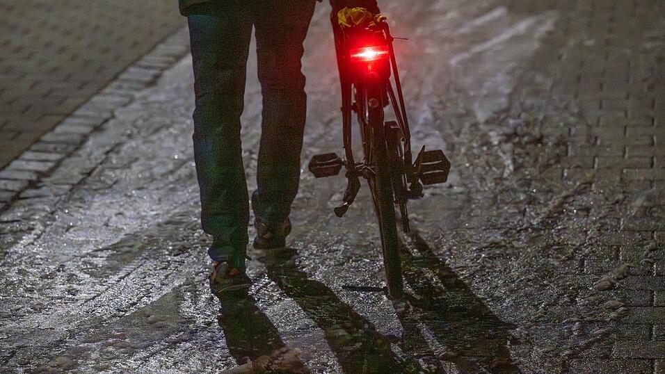 Ein Mann schiebt sein Fahrrad auf einer vereisten Stra&szlig;e.