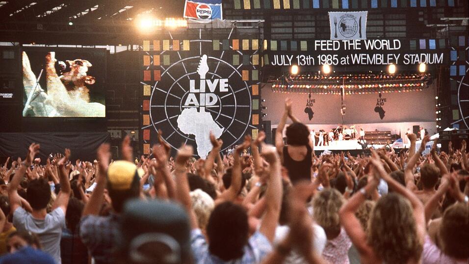 Die Fans jubeln. Das gr&ouml;&szlig;te Rockkonzert aller Zeiten, organisiert von dem irischen Musiker Bob Geldof, fand am 13. und 14. Juli 1985 gleichzeitig in London und Philadelphia/USA statt und wurde via Satellit in &uuml;ber 25 L&auml;nder live &uuml;bertragen. Neben Queen beteiligten sich internationale Superstars wie David Bowie, Elton John, John Baez, Tina Turner und Bob Dylan an dem 16-st&uuml;ndigen Musikspektakel, das durch Spenden, Eintrittskarten und Fernsehrechte 82 Millionen Pfund (280 Millionen Mark) f&uuml;r die Hungernden in Afrika einbrachte.
