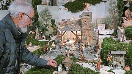 Der Krippenbauer Alfons Krinner mit dem neugeborenen Jesuskind im Stall von Betlehem, zu dem die Hirten eilen, um es anzubeten - darunter die dargestellte Taufe Jesu am Jordan.