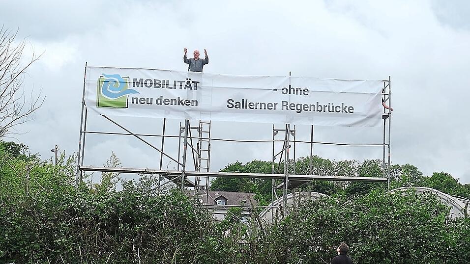 An einem Gerüst auf dem Geländer der vom Brückenbau betroffenen Gärtnerei Hauner hängt seit Samstag ein neun Meter langes Banner des Bündnisses „Mobilität neu denken“.