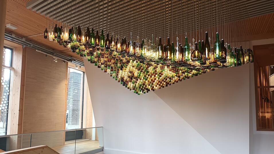 Funkelnder Blickfang im Eingangsbereich: die h&auml;ngende 'Welle' des Straubinger K&uuml;nstlers Tom Kristen aus tausend verschiedenfarbigen und beleuchteten Flaschen.