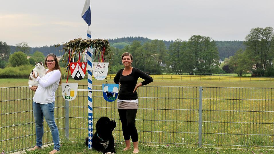 Karin (l.) und Andrea Bugel haben in ihrem Garten ihren eigenen Mini-Maibaum aufgestellt. Die Schwestern aus Train (Kreis Kelheim) verkaufen Maibaumsets zum Selbstgestalten.