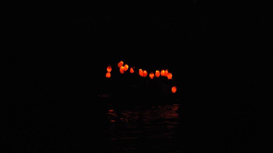 Bunt beleuchtete Boote fahren bei der Lampionfahrt über die Donau.