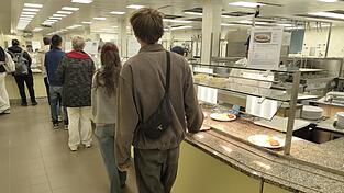 Lena Schmidt und Felix Bernard gehen an der Ausgabe der uni Mensa direkt an den Fleisch-Gerichten vorbei auf die veganen und vegetarischen Optionen zu.