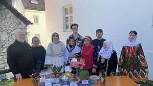 Die Organisatoren und Frauen in traditionellen Festgew&auml;ndern hinter den symbolreichen Nowruz-Gegenst&auml;nden.