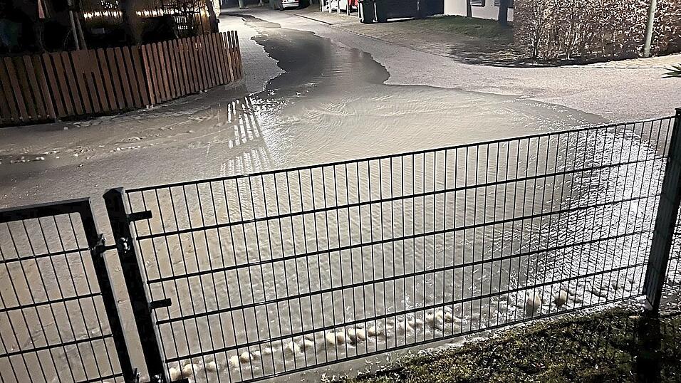 An mehreren Stellen entlang der Bruchlinie hinterm Zaun quillt Wasser. Etwa 20.000 Liter fluten so in kurzer Zeit die Stra&szlig;e.