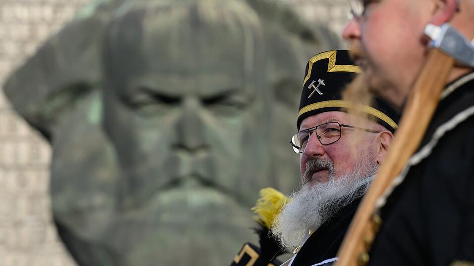Zum Abschluss des Kulturhauptstadtjahres in Chemnitz ziehen Teilnehmer der Bergparade im traditionellen Habit am Karl-Marx-Monument vorbei.