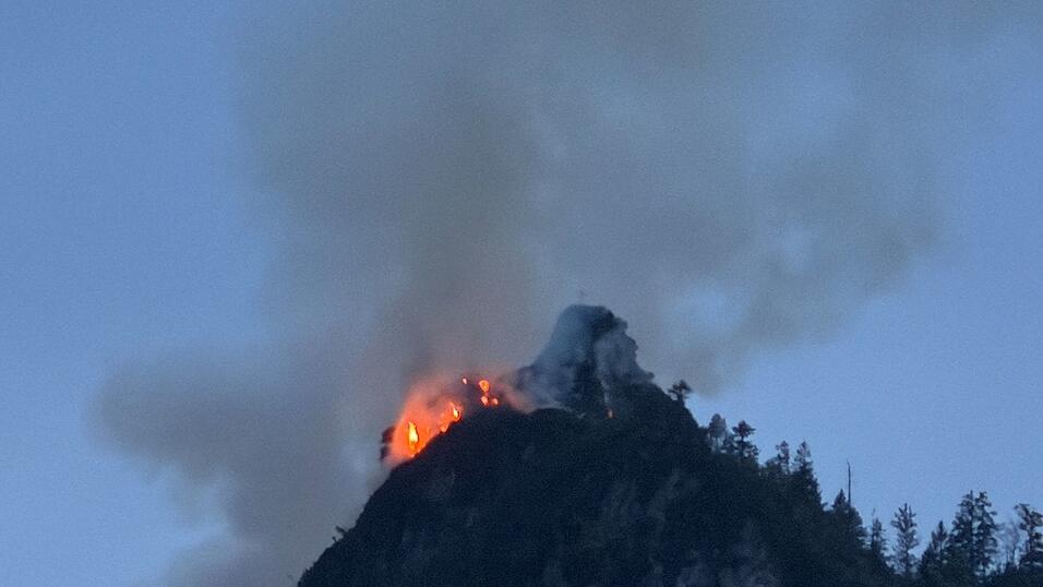 Noch immer steigen gro&szlig;e Rauchwolken aus einem bewaldeten Berg bei Ruhpolding (Landkreis Traunstein) auf.