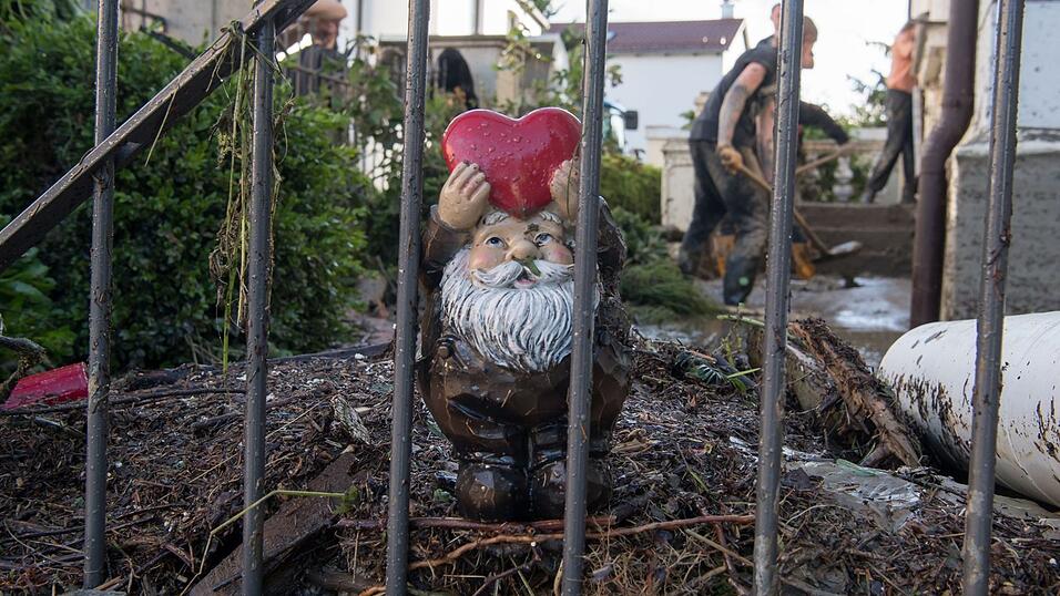 Ein Gartenzwerg mit einem roten Herz in der Hand steht am 2. Juni 2016 in Simbach am Inn am Zaun eines Vorgartens, in dem Helfer den Schlamm wegschaufeln.