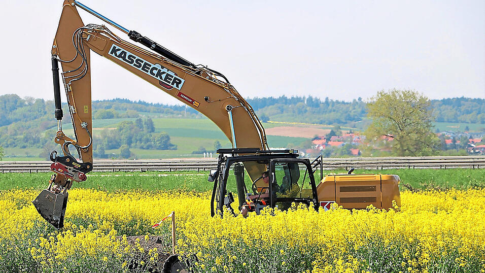 Einfamilienh&auml;user rechts im Hintergrund, davor die Autobahn und im Bildvordergrund ein Acker - auf diesem Foto ist viel zu sehen der heutigen Kultur. Der Bagger tr&auml;gt die oberen Bodenschichten ab - denn darunter k&ouml;nnten sich Hinweise auf fr&uuml;hgeschichtliche Siedlungen befinden.