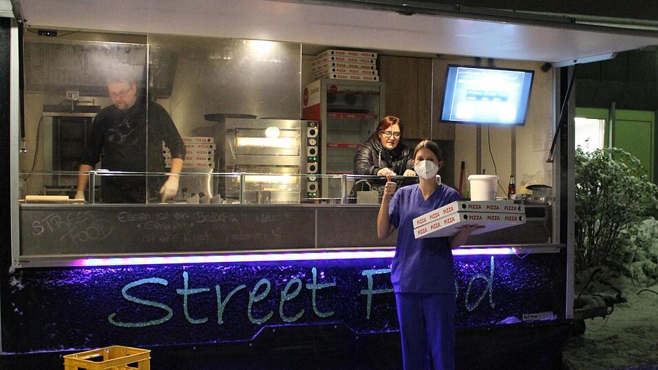Eine Krankenschwester der Intensivstation der Arberlandklinik Viechtach holt zwei Pizzakartons f&uuml;r sich und ihre Kollegen ab. Marco Fischer (li.) und Ulrike Wagner von Marco Street Food verk&ouml;stigen die Angestellten umsonst mit Pizza und Getr&auml;nken.